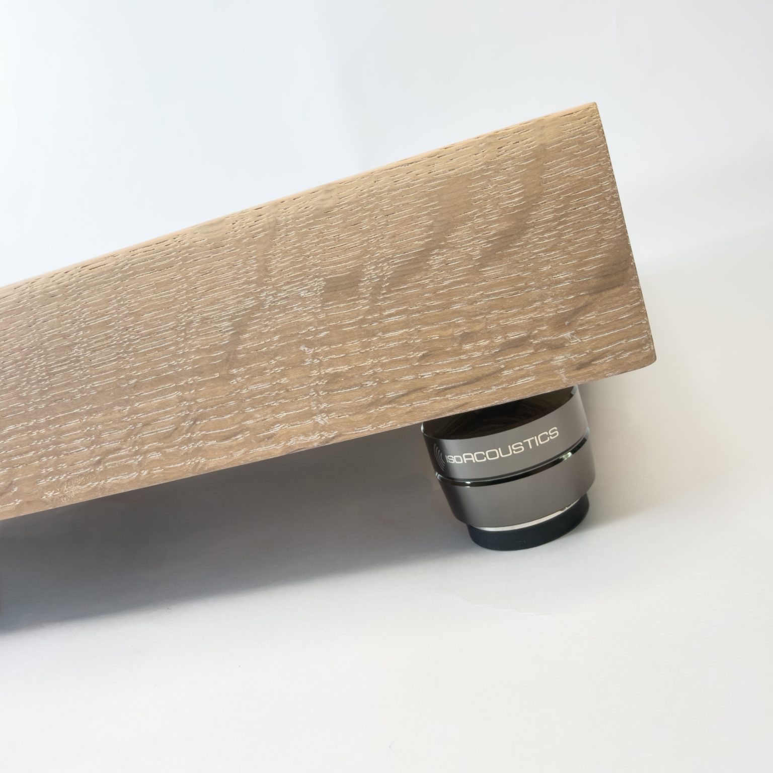 Quarter-sawn white oak edge showing ray-fleck figure above an IsoAcoustics Gaia III isolator